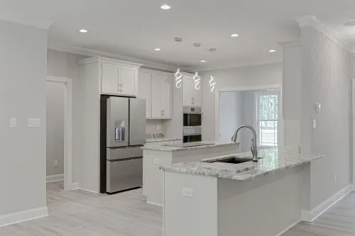 New modern kitchen with bright white cabinets and marble countertops